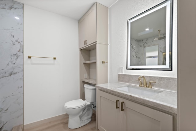 full bath featuring toilet, wood finished floors, a marble finish shower, and vanity
