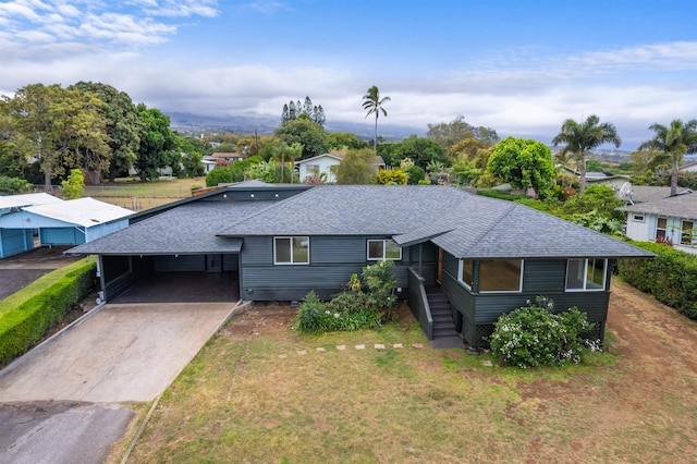 view of front of property with a front yard, an attached carport, driveway, and roof with shingles