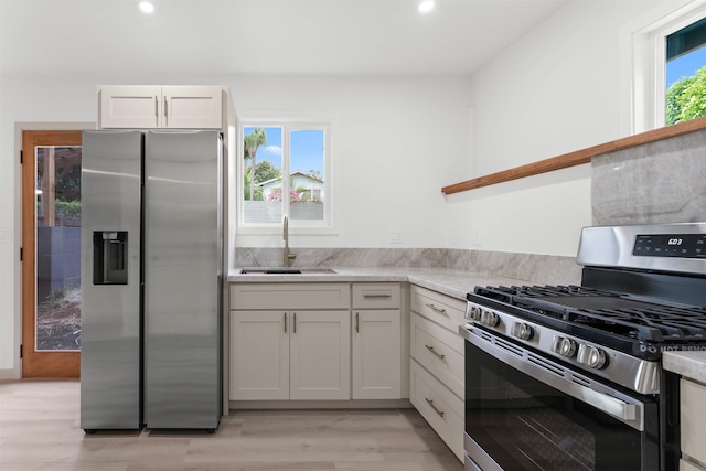 kitchen with light wood-type flooring, recessed lighting, white cabinetry, appliances with stainless steel finishes, and a sink