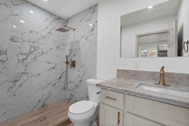bathroom featuring toilet, vanity, a marble finish shower, and wood finished floors