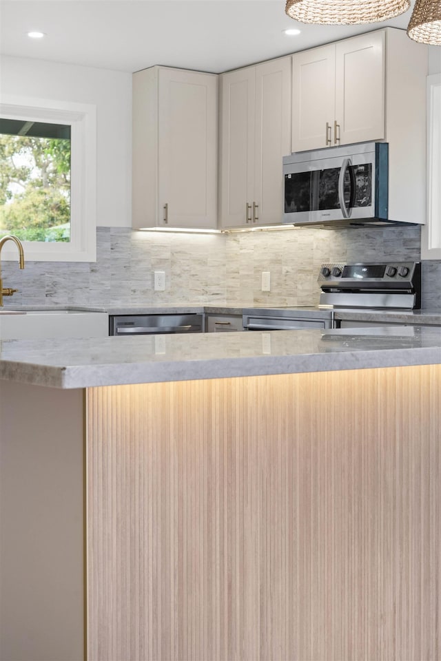 kitchen featuring appliances with stainless steel finishes, recessed lighting, white cabinetry, decorative backsplash, and a sink