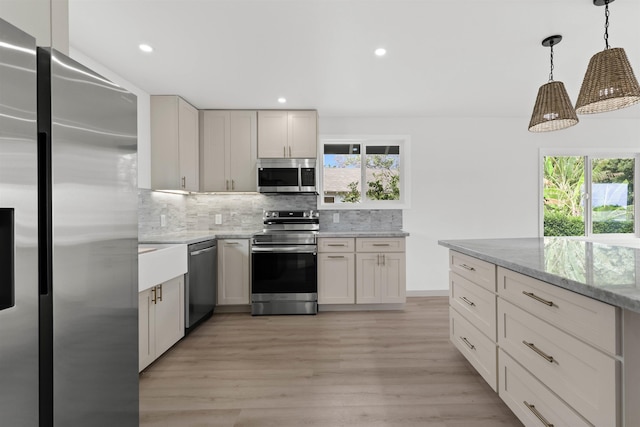 kitchen featuring stainless steel appliances, tasteful backsplash, light wood-style flooring, and a wealth of natural light