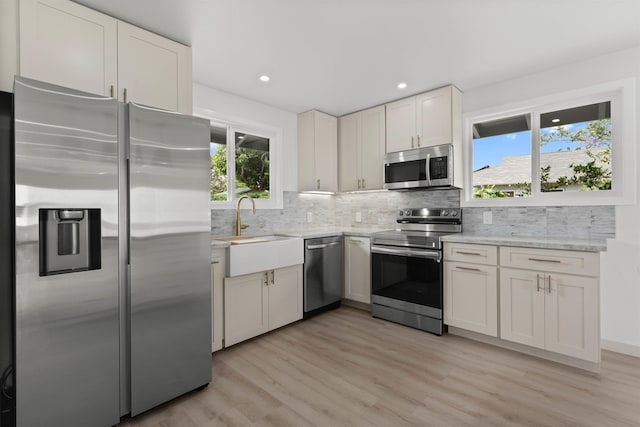 kitchen with light wood-style flooring, a sink, appliances with stainless steel finishes, recessed lighting, and decorative backsplash
