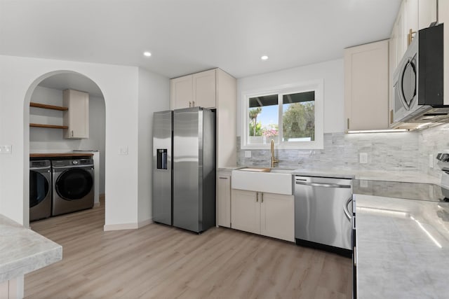kitchen featuring separate washer and dryer, a sink, light countertops, light wood-type flooring, and appliances with stainless steel finishes