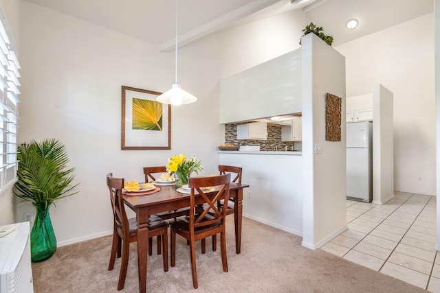 tiled dining space featuring vaulted ceiling with beams