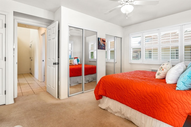 carpeted bedroom featuring ceiling fan and two closets