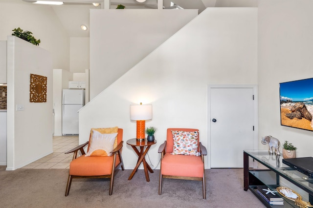 sitting room with high vaulted ceiling and light colored carpet