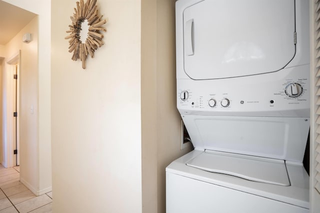 laundry room with stacked washer and clothes dryer and light tile patterned floors