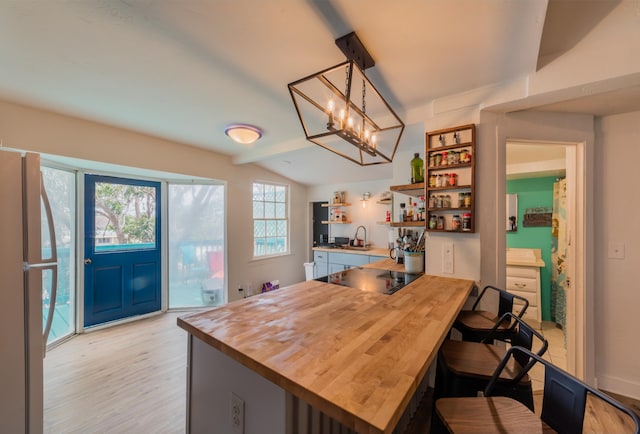 kitchen with a kitchen bar, black electric stovetop, sink, refrigerator, and kitchen peninsula