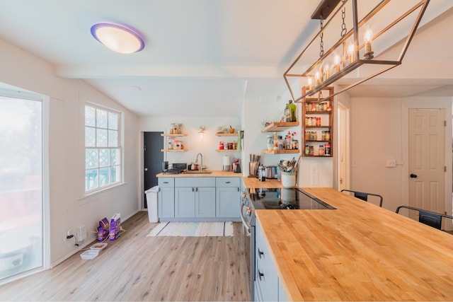 kitchen featuring wooden counters, light hardwood / wood-style floors, vaulted ceiling with beams, sink, and stainless steel range with electric cooktop