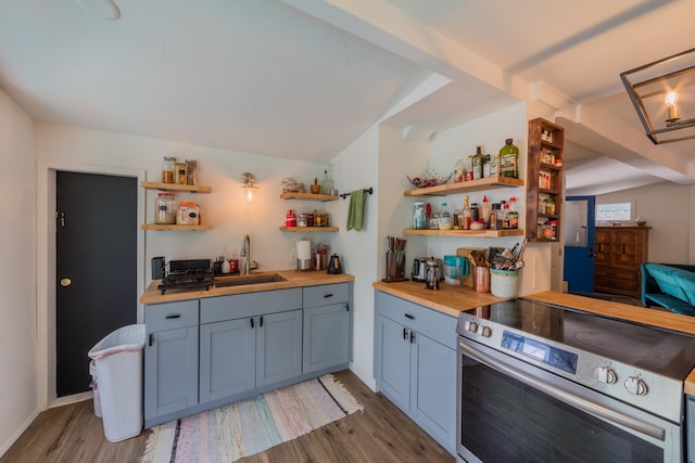 kitchen with electric stove, wooden counters, sink, and light hardwood / wood-style floors