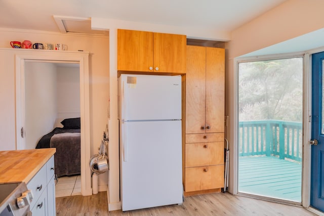 kitchen with wooden counters, light hardwood / wood-style flooring, stainless steel electric range oven, and white fridge