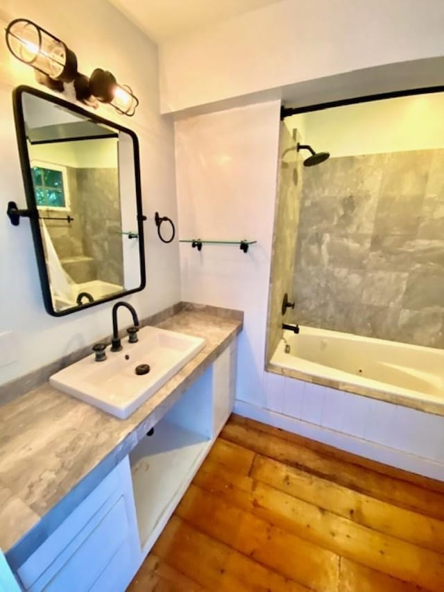 full bath featuring vanity, tiled shower / bath, and wood finished floors