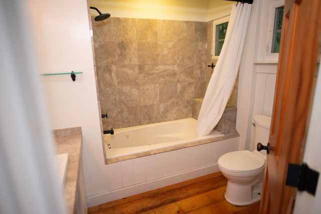 bathroom featuring tiled shower / bath, toilet, and wood finished floors