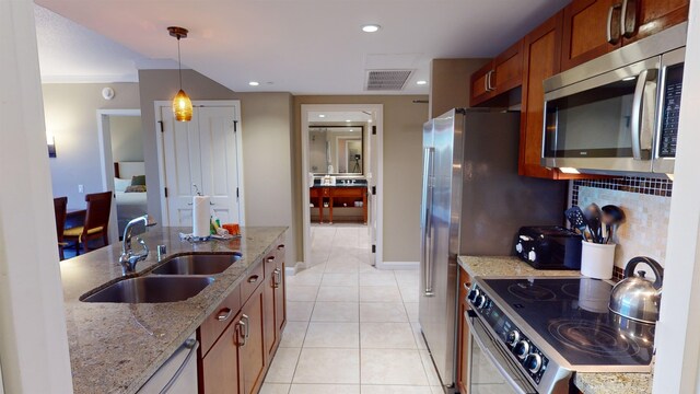 kitchen with light stone countertops, light tile patterned floors, sink, decorative light fixtures, and stainless steel appliances