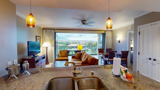 kitchen with decorative light fixtures, sink, crown molding, light stone countertops, and ceiling fan