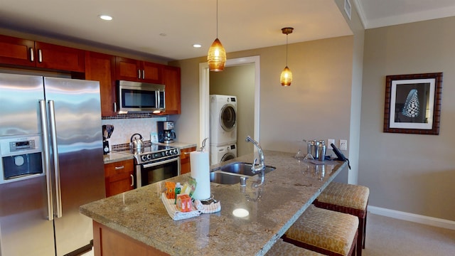 kitchen featuring light carpet, hanging light fixtures, light stone counters, and stainless steel appliances