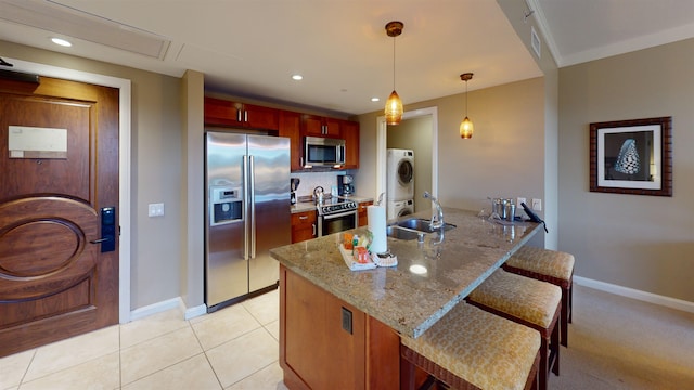 kitchen with hanging light fixtures, appliances with stainless steel finishes, light stone countertops, light tile patterned floors, and sink