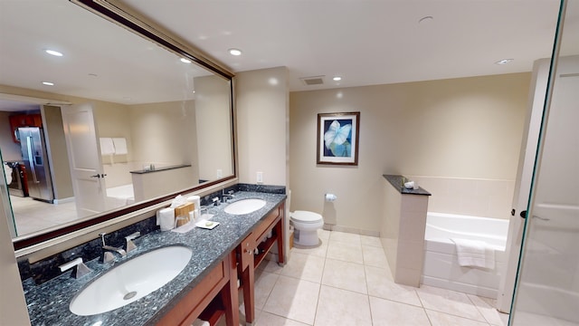 bathroom featuring a washtub, toilet, vanity, and tile patterned floors