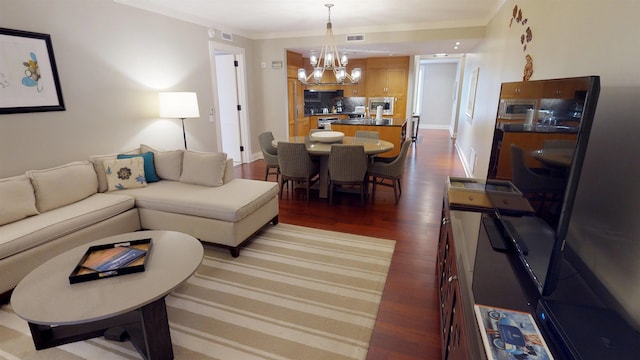 living room with ornamental molding, dark wood-type flooring, and a chandelier