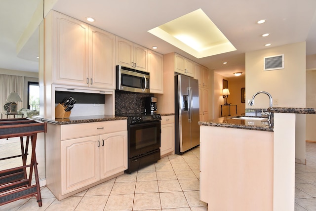 kitchen featuring appliances with stainless steel finishes, sink, light tile flooring, and dark stone countertops