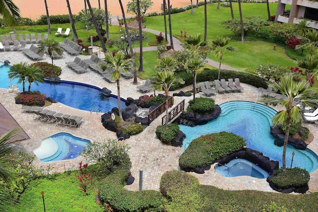 pool at dusk with a yard, a community hot tub, and a patio area