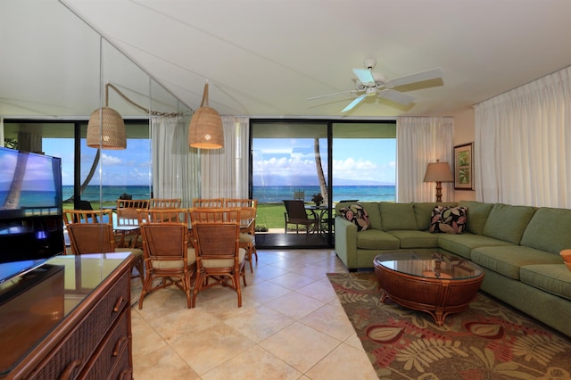 living room featuring light tile patterned flooring, a water view, ceiling fan, and a wall of windows