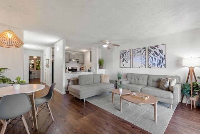 living room featuring a textured ceiling, ceiling fan, and dark wood-type flooring