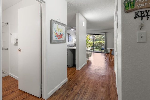 corridor featuring wood-type flooring and a textured ceiling