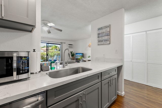 kitchen featuring gray cabinetry, sink, appliances with stainless steel finishes, dark hardwood / wood-style flooring, and light stone counters