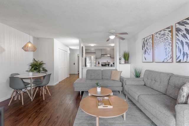 living room featuring ceiling fan, dark wood-type flooring, and a textured ceiling