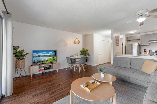 living room with dark hardwood / wood-style floors, ceiling fan, and a textured ceiling