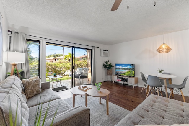 living room featuring an AC wall unit, ceiling fan, hardwood / wood-style floors, and a textured ceiling