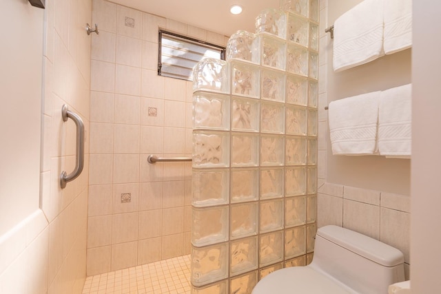 bathroom with tile walls, toilet, and a tile shower