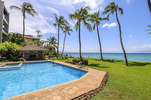 view of swimming pool with a water view, a gazebo, a lawn, and an in ground hot tub