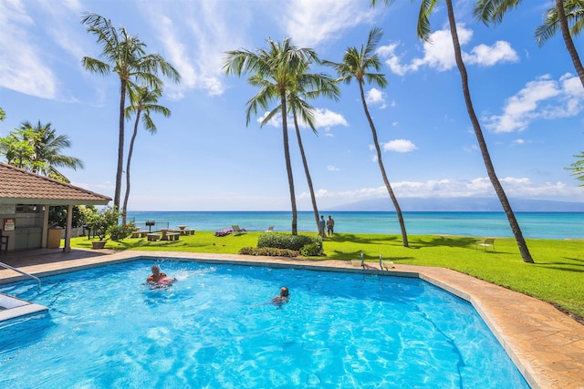 view of swimming pool with a yard and a water view