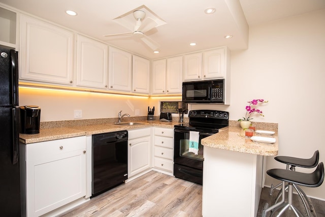 kitchen featuring sink, white cabinetry, black appliances, and light wood-type flooring