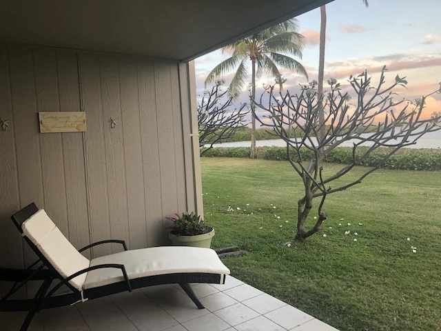 patio terrace at dusk with a water view and a lawn