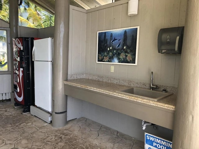 kitchen featuring sink, white fridge, and wood walls