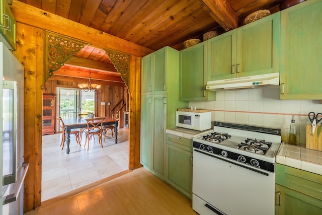 kitchen with under cabinet range hood, green cabinetry, tile countertops, and white appliances
