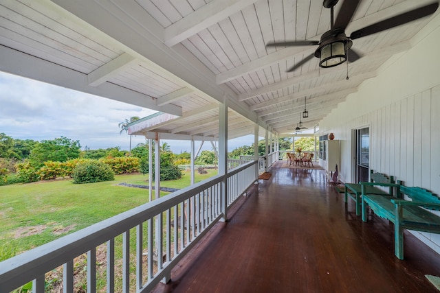 wooden deck featuring outdoor dining area, a lawn, and ceiling fan