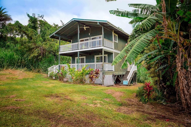 rear view of house with a balcony, stairs, a wooden deck, and a lawn