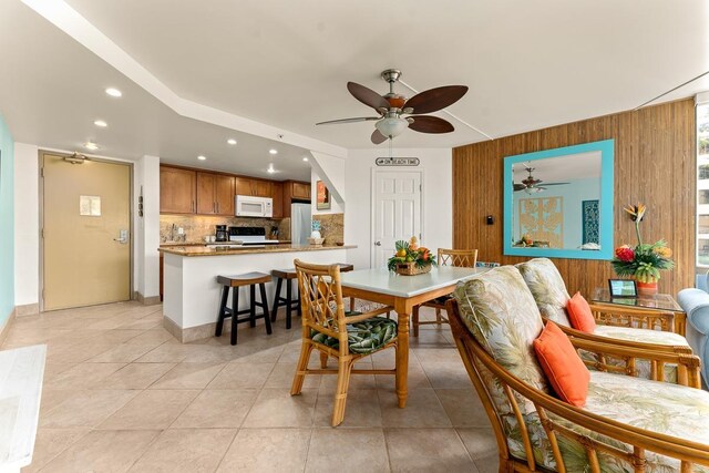 dining space with wooden walls, light tile patterned flooring, a ceiling fan, and recessed lighting