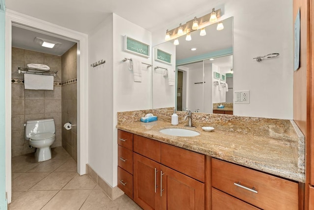 bathroom with tile walls, vanity, toilet, and tile patterned floors