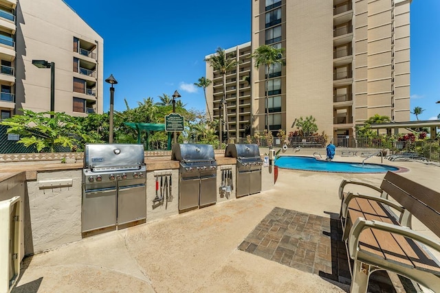 exterior space featuring a grill, a community pool, and an outdoor kitchen