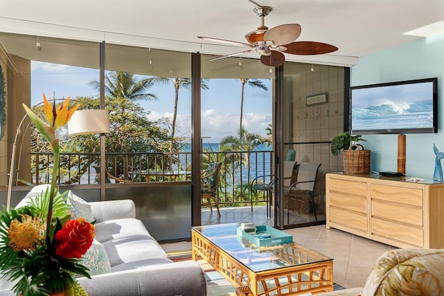 living area with light tile patterned floors, ceiling fan, and a water view