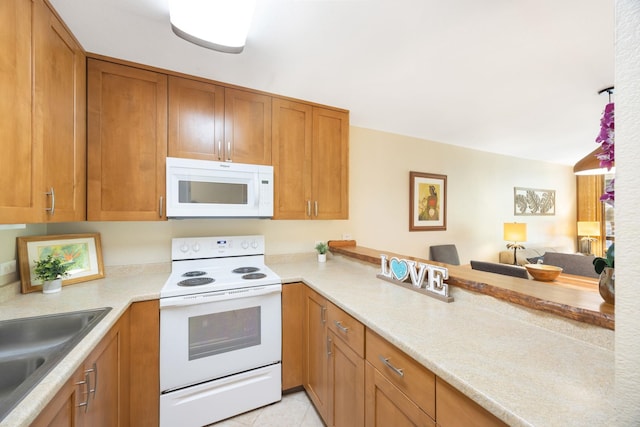 kitchen featuring brown cabinets, white appliances, light countertops, and a sink