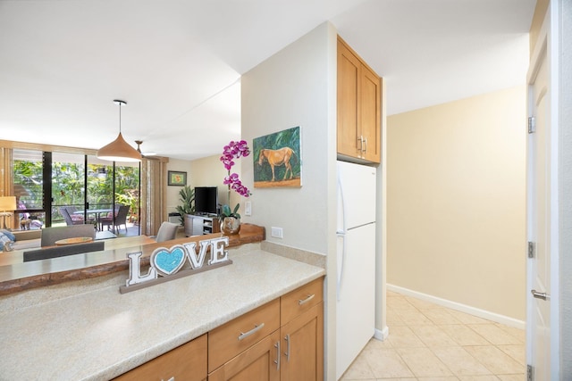 kitchen featuring pendant lighting, freestanding refrigerator, light countertops, light tile patterned floors, and baseboards