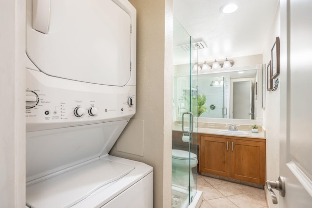 washroom with visible vents, light tile patterned floors, laundry area, stacked washer and clothes dryer, and a sink