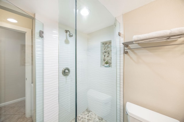 full bathroom featuring toilet, a stall shower, and tile patterned flooring